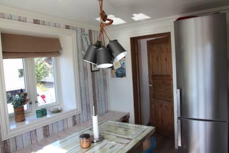 a kitchen with a stainless steel refrigerator and a table at Koselig hus nært havet i Lofoten, Kabelvåg in Kabelvåg