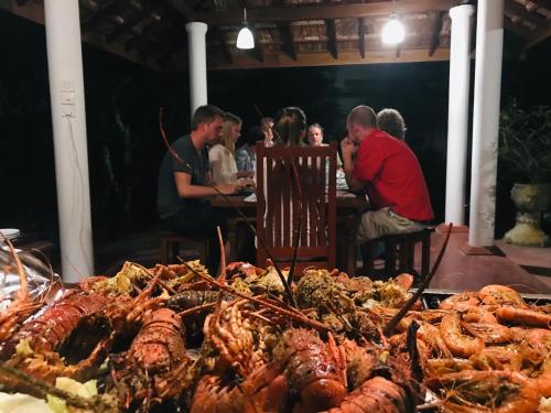 a group of people sitting at a table with food at Villa 45 - Balapitiya in Balapitiya