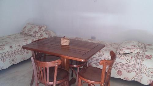 La Cabañita de Tilcara في تيلكارا: طاولة وكراسي خشبية في غرفة بها سرير