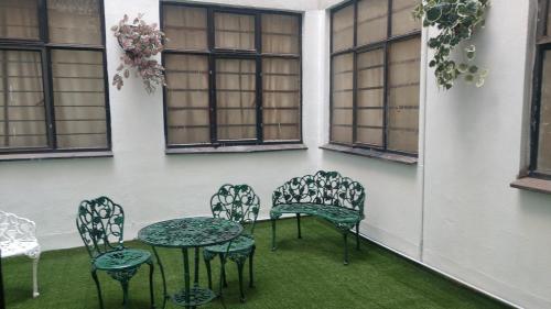 a patio with chairs and a table and windows at Pension Zocalo in Mexico City