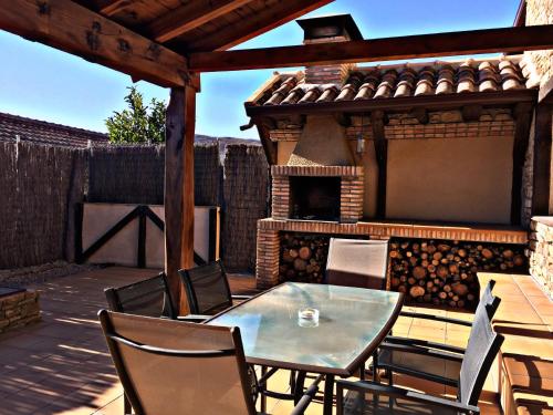 a patio with a table and chairs and a fireplace at El Corral De Concejo in Horcajuelo de la Sierra