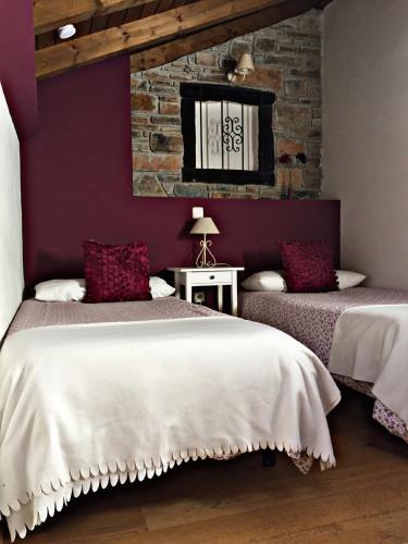 a bedroom with two beds and a brick wall at El Corral De Concejo in Horcajuelo de la Sierra
