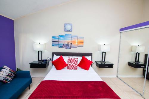 a bedroom with a bed with red pillows and a blue couch at The Oasis I, Portmore Country Club in Portmore