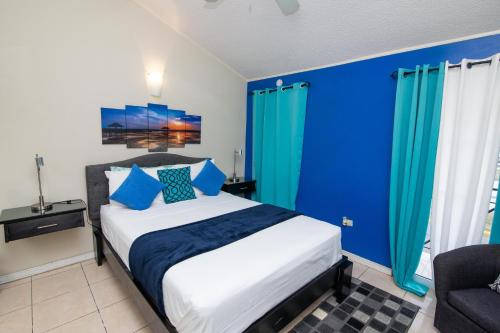 a bedroom with blue walls and a bed with blue curtains at The Oasis I, Portmore Country Club in Portmore