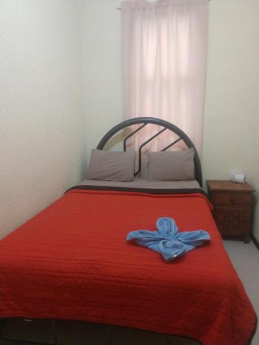 a bed with a red blanket with a blue bow on it at Pension Zocalo in Mexico City