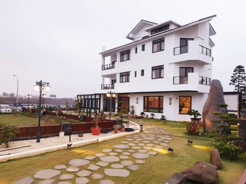 a white building with a pond in front of it at Ocean View Hall B&B in Magong