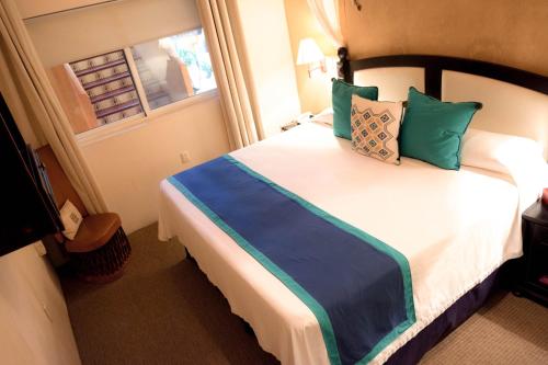 a bedroom with a large bed with blue and green pillows at El Chante Spa Hotel in Jocotepec