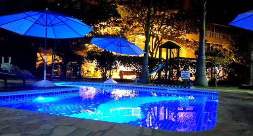 una piscina con sombrillas por la noche en Pousada Pedra Salgada, en Bombinhas