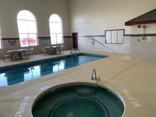 a swimming pool in a building with chairs and tables at Brentwood Inn & Suites in Hobbs