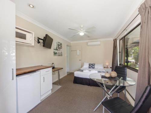 um quarto com uma cama e uma mesa num quarto em Narimba Motel em Port Macquarie