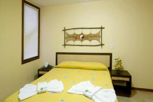 RESORT SOLAR PIPA CASA na frente da pisina في بيبا: غرفة نوم بسرير اصفر عليها مناشف