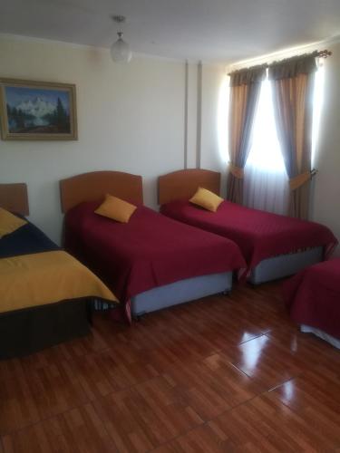 two beds in a room with wooden floors at Casa Huespedes Angoba in Arica