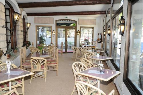 un restaurant avec des tables et des chaises et une fenêtre dans l'établissement Grand Hôtel du Cours, à Sisteron