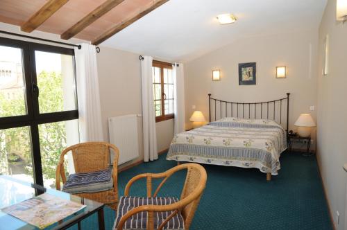 a bedroom with a bed and a table and chairs at Grand H&ocirc;tel du Cours in Sisteron
