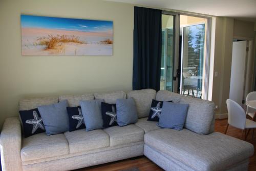 a living room with a couch with blue pillows at Beachside Luxury Apartments One & Two Bedroom in Beachfront Oaks Pier Building in Glenelg