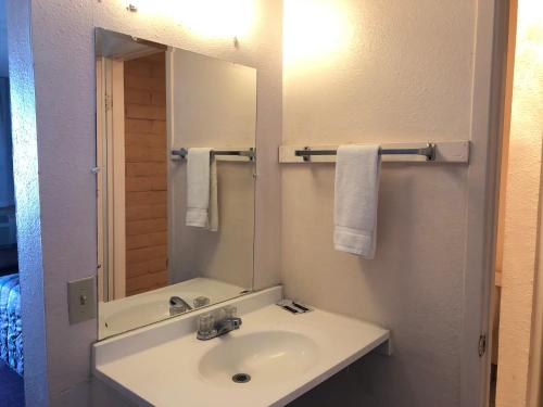 a bathroom with a sink and a mirror and towels at Deluxe Inn Motel in Sparks