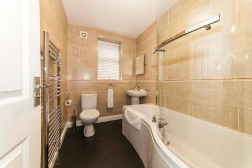 a bathroom with a tub and a toilet and a sink at Belmont Apartments in Billingham