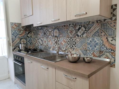 a kitchen with a sink and a stove and tiles at Appartamento TE&ME in Cefalù