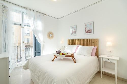 a white bedroom with a large bed with a table on it at Gran Via Balconies in Granada