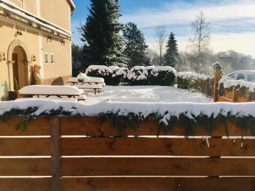 a fence covered in snow next to a building at Pension Žacléřský Medvěd in Žacléř