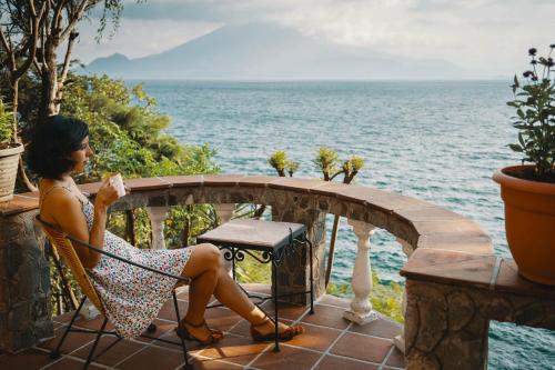 a woman sitting in a chair overlooking the ocean at Hotel La Casa del Mundo in Jaibalito