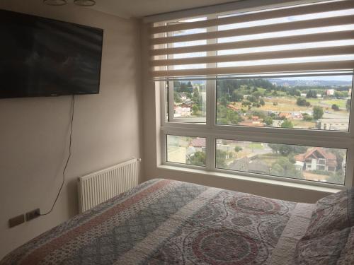a bedroom with a bed and a large window at Departamento Parque Urbano 1710 in Concepción
