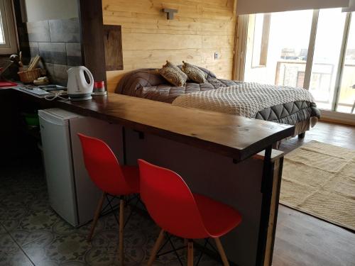 a bedroom with a bed and a desk with red chairs at SaldeMar Playa Hermosa in Pichilemu