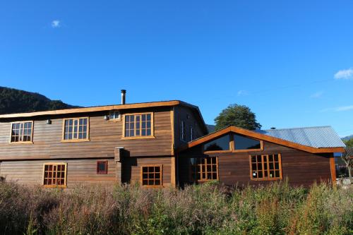 ein großes Holzhaus mit einem Gamer-Dach in der Unterkunft Los Mañíos Del Queulat Puyuhuapi in Puerto Puyuhuapi