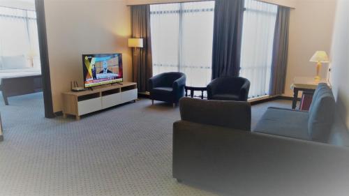 a living room with a couch and chairs and a television at Grand Service Apartment @ Times Square in Kuala Lumpur