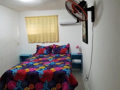 Schlafzimmer mit einem Bett mit einer bunten Bettdecke und einem Ventilator in der Unterkunft Lucy Rooms in Juan Dolio