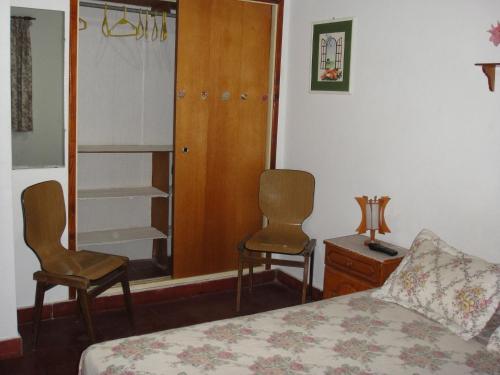 un dormitorio con cama y dos sillas y un armario en la Avenida 2, 3344 de Villa Gesell