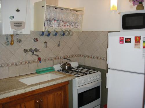 cocina con encimera y heladera blanca en Avenida 2, 3344 en Villa Gesell