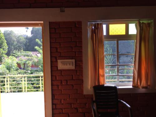a room with two windows and a brick wall at Marsim Holiday Resort in Vythiri