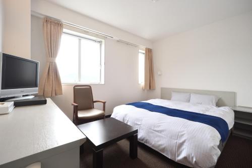 a hotel room with a bed and a television at Uwajima Oriental Hotel in Uwajima
