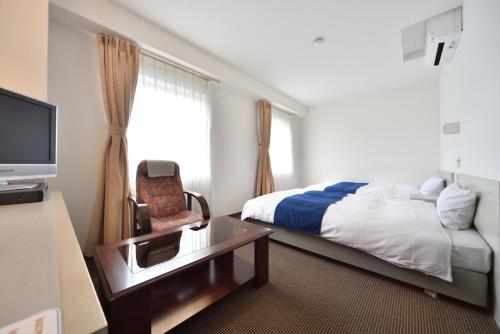 ein Hotelzimmer mit einem Bett und einem TV in der Unterkunft Uwajima Oriental Hotel in Uwajima