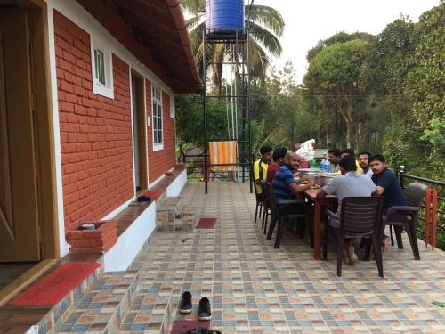 a group of people sitting at a table on a patio at Marsim Holiday Resort in Vythiri