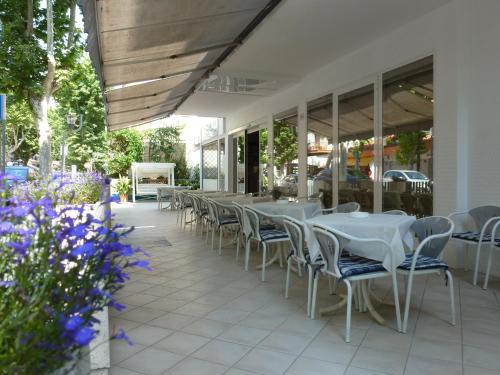 szereg stołów i krzeseł na patio w obiekcie Hotel Gioiella w Rimini