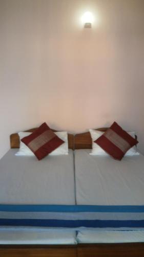 a bed with red and white pillows on it at Sunny Lanka Guest House in Matara
