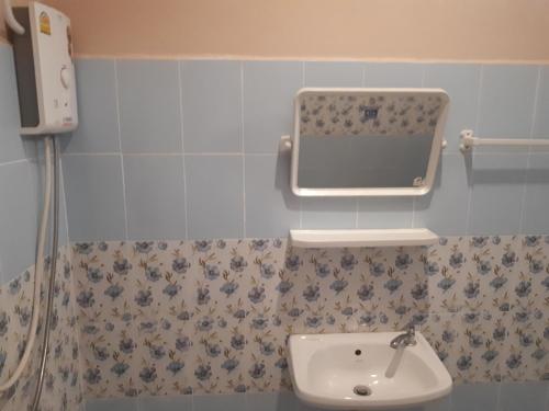 ein Bad mit einem Waschbecken und einem Wandspiegel in der Unterkunft Pornsomkit room in Ban Ai Hit