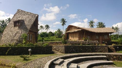 ein Haus mit einem Strohdach neben einem Gebäude in der Unterkunft Balkondes Kembanglimus in Borobudur