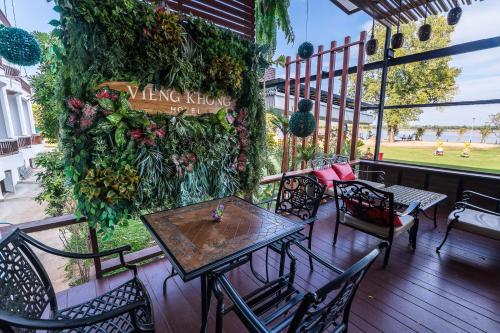 a patio with tables and chairs and a green wall at Vieng Khong Hotel in Mukdahan