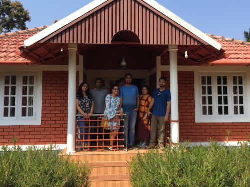 a group of people standing on the front porch of a house at Marsim Holiday Resort in Vythiri