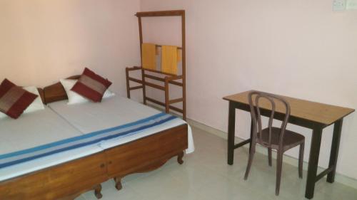 a bedroom with a bed and a table and a chair at Sunny Lanka Guest House in Matara