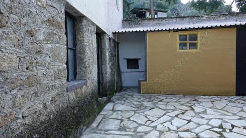 a building with a yellow door next to a stone wall at The old olive mill house in Aegae