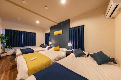 grupa łóżek w pokoju z oknami w obiekcie Kyoan Shion w mieście Kioto