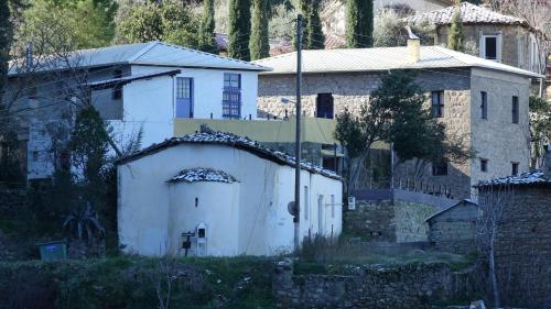 a white building and a house with a wall at The old olive mill house in Aegae
