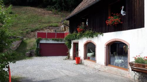 een wit gebouw met een rode deur en een garage bij Le moulin des automates in Fréland