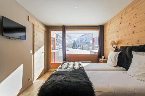 a hotel room with two beds and a window at Maisons de montagne Le Samovar in Val dʼIsère