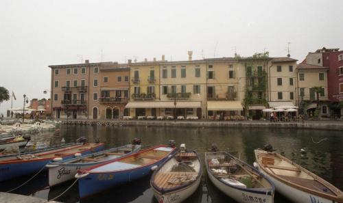 a group of boats in the water near buildings at Hotel da Roberto in Lazise