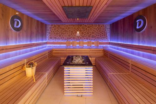 a sauna with blue lights on the walls and benches at Dilly - Das Nationalpark Resort in Windischgarsten